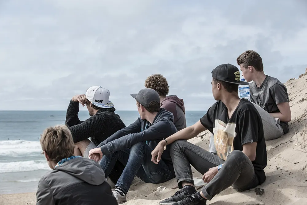 Groupe de jeunes assis sur la dune face à la mer
