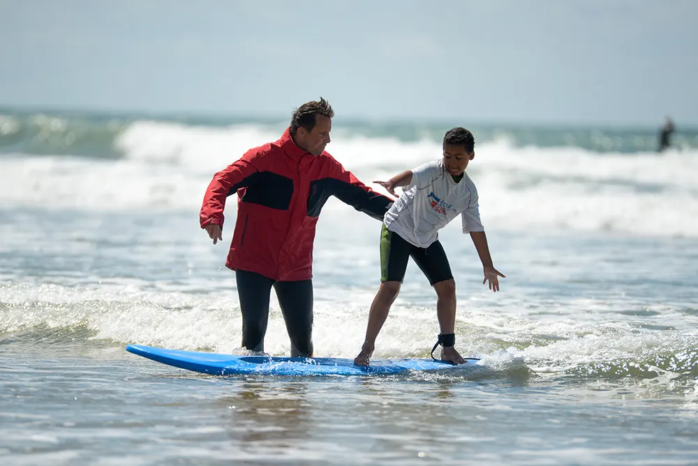 Moniteur qui conseille un élève dans les vagues