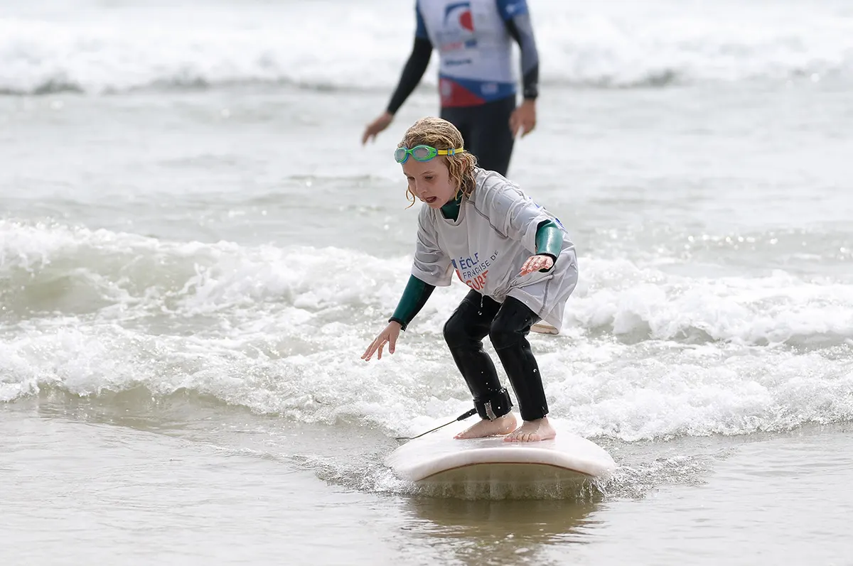 Un moniteur et un enfant dans l'eau, planche de surf