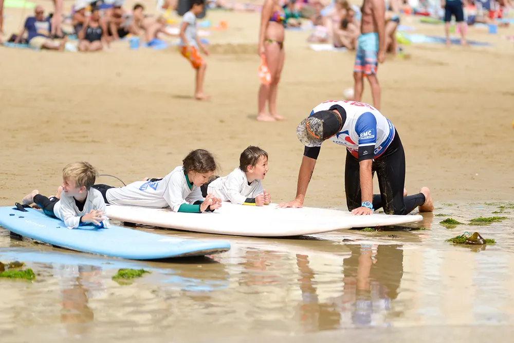 Moniteur et enfants sur leurs planches dans les vagues
