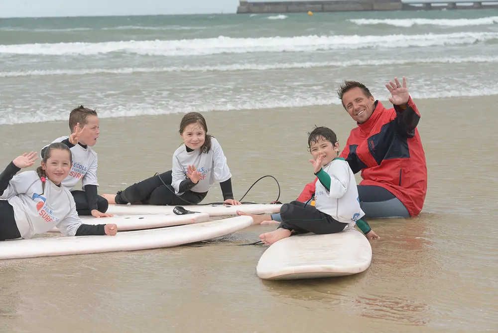 Groupe d'élèves assis sur le sable avec leurs planches