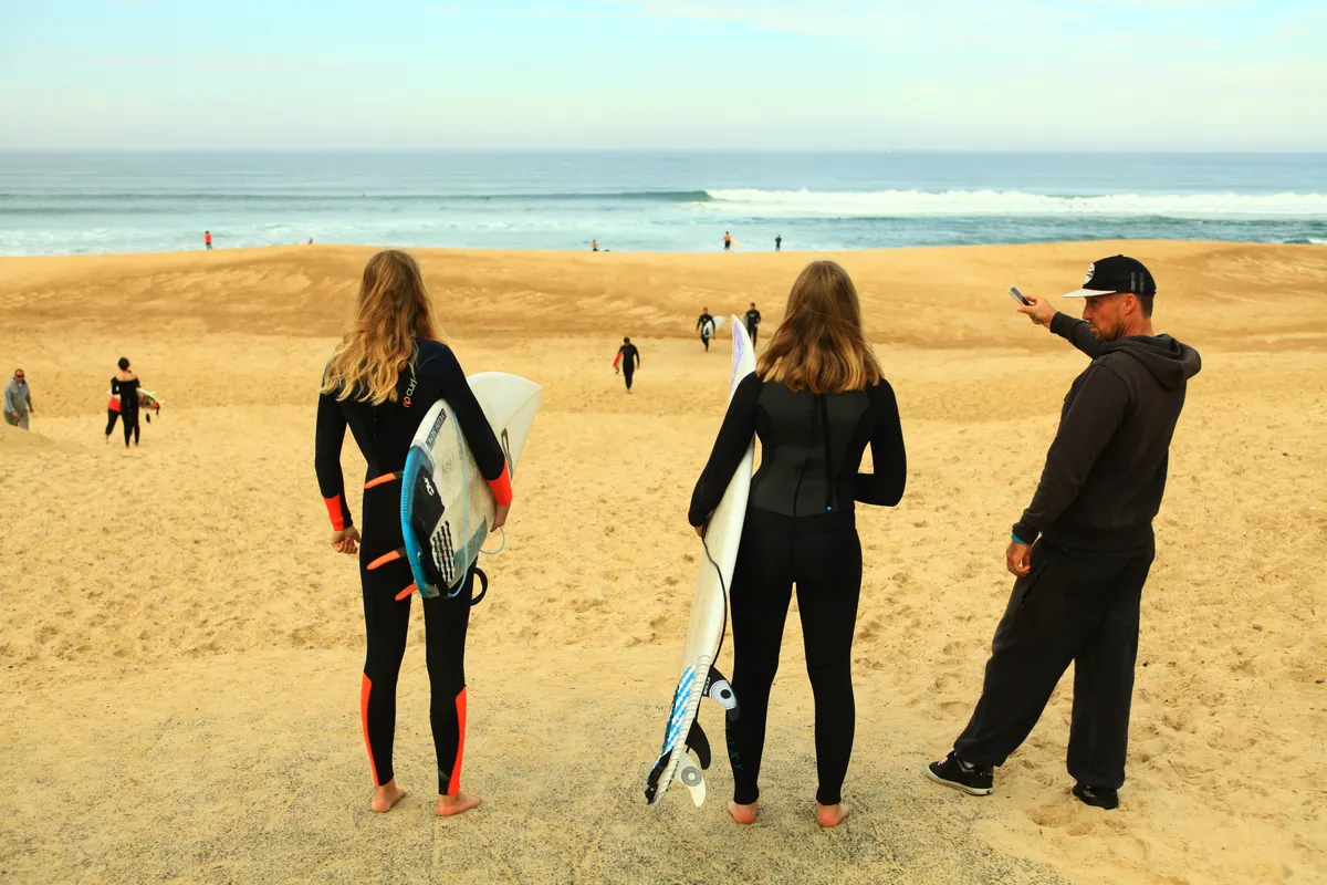 Élèves en combinaison sur la plage avec leurs planches